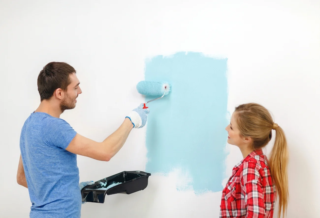 man repainting a wall after fixing peeling milk paint