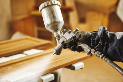 man using a spray gun with a wood finish for richer penetration 