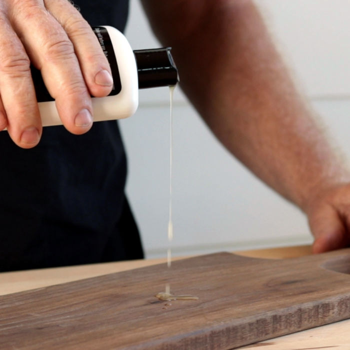 man pouring oil in wood cutting board