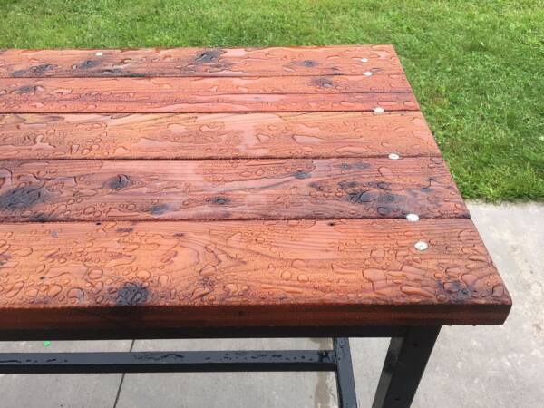 outdoor furniture with warm glow from outdoor defense oil and water beading on surface of finished wood