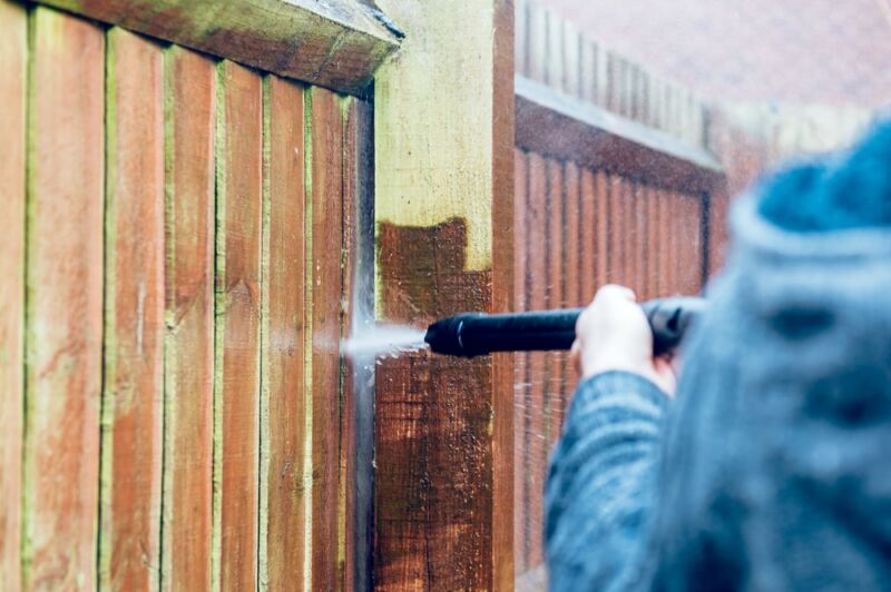 image of man cleaning fence for painting