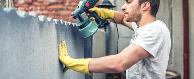 man spraying paint on wall