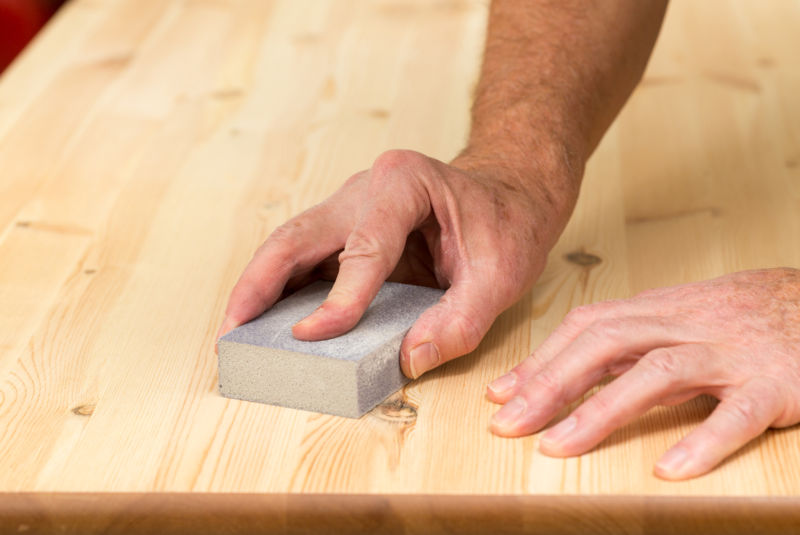 man sanding wood properly preparing it for wood staining project